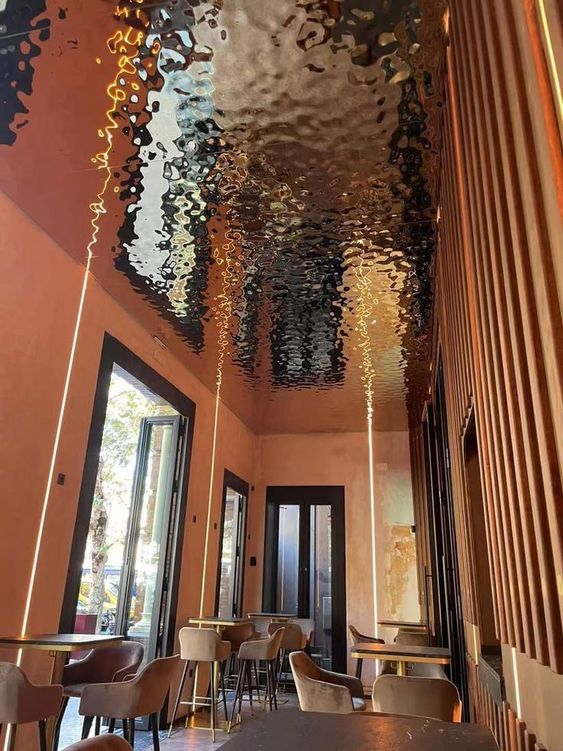 Salle de restaurant aux matières chaleureuses et plafond réfléchissant, créant une expérience immersive et enveloppante.