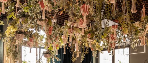 Aménagement d'un restaurant avec banquette, grande table conviviale et décoration végétale suspendue. Les matériaux, les textiles et la lumière créent une atmosphère accueillante tout en répondant aux exigences d'un ERP.