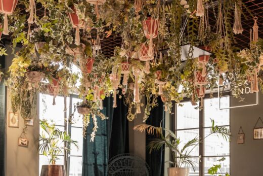 Aménagement d'un restaurant avec banquette, grande table conviviale et décoration végétale suspendue. Les matériaux, les textiles et la lumière créent une atmosphère accueillante tout en répondant aux exigences d'un ERP.