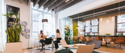 Espace de travail lumineux avec fauteuils autour d’un tapis vert, table haute et salle